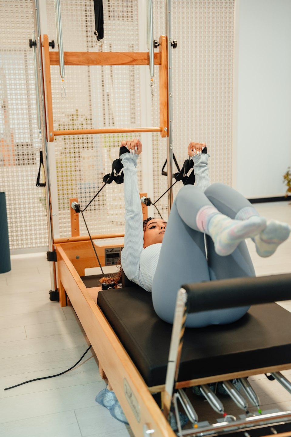 Mujer haciendo ejercicios de pilates en una máquina de reformer.