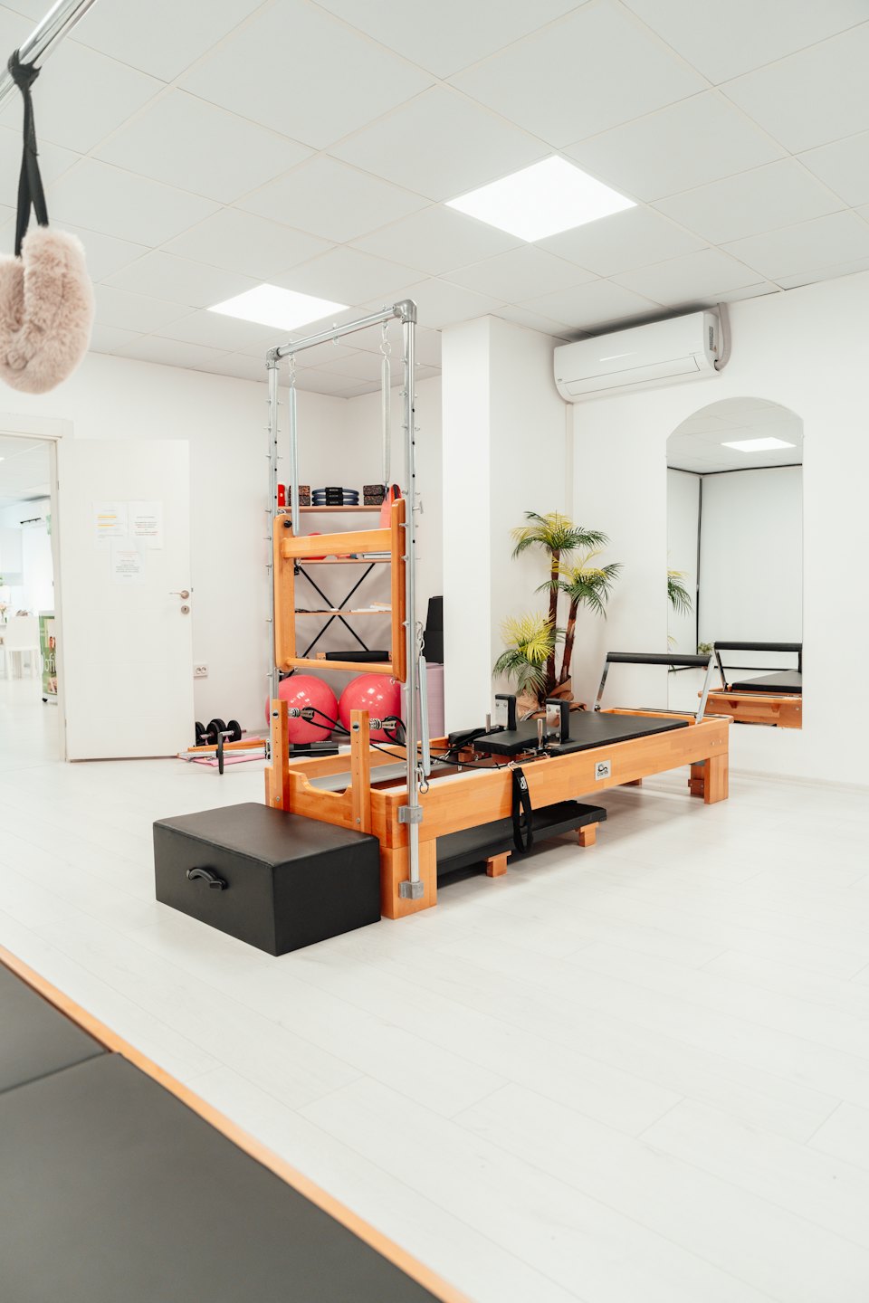 Una máquina de Pilates reformer se encuentra en un estudio de ejercicios luminoso.